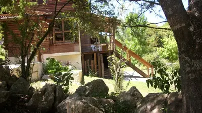 a house with a deck and rocks in the yard at Cabaña Atha Iti in Villa General Belgrano