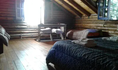 a log cabin bedroom with a bed and a teddy bear at Cabaña Atha Iti in Villa General Belgrano