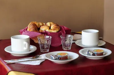 a table with plates and cups and a basket of bread at Embajador Hotel in Villa Carlos Paz