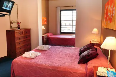 a bedroom with two beds and a television in it at Embajador Hotel in Villa Carlos Paz