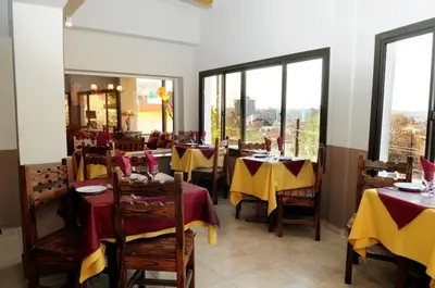a restaurant with tables and chairs with yellow and red table cloth at Embajador Hotel in Villa Carlos Paz