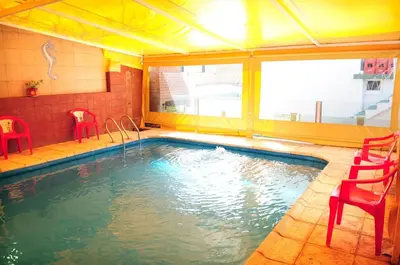 a swimming pool with red chairs and a large window at Embajador Hotel in Villa Carlos Paz