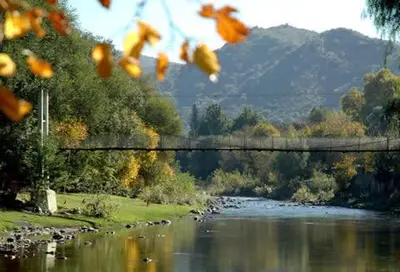 a bridge over a river with a mountain in the background at La casa de Almirall in Santa Rosa de Calamuchita