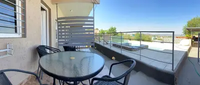 a glass table and chairs on a balcony with a staircase at Sierras Apartamentos in Villa Santa Cruz del Lago