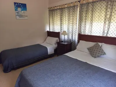 a bedroom with two beds and a window with curtains at Hosteria Valle Azul in Villa del Dique