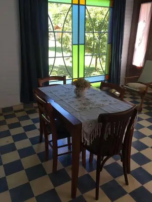 a dining room table with chairs and a colorful window at Raco De La Calma in Nono