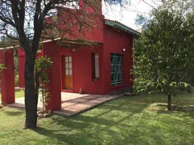 a red house with a tree in front of it at Raco De La Calma in Nono