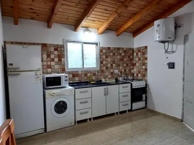 a kitchen with a refrigerator and a washing machine at Cabañas Cuncumen in Los Reartes
