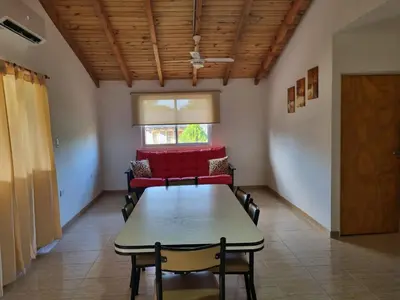 a dining room with a table and a red couch at Cabañas Cuncumen in Los Reartes