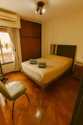 a bedroom with a bed and a chair and a window at Apartamento Andres in Cordoba