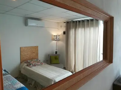 a mirror in a room with a bed and a window at EFE Aparts in Mina Clavero