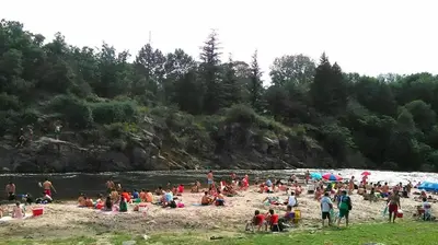 a group of people on a beach near a river at Cabañas Campo Huasi in Santa Rosa de Calamuchita