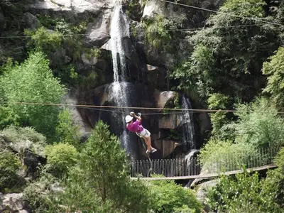 a person jumping on a zip line in front of a waterfall at Cabañas Campo Huasi in Santa Rosa de Calamuchita