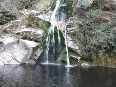 a waterfall in the middle of a body of water at Cabañas Campo Huasi in Santa Rosa de Calamuchita