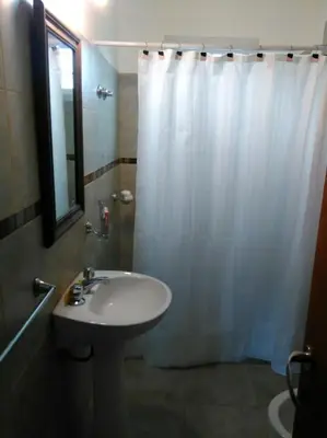 a bathroom with a white shower curtain and a sink at Cabañas Campo Huasi in Santa Rosa de Calamuchita