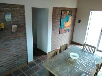 a dining room with a table and a brick wall at Cabañas Campo Huasi in Santa Rosa de Calamuchita