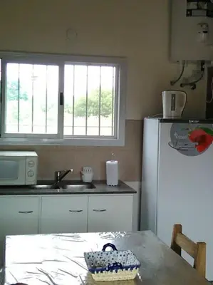 a kitchen with a table and a white refrigerator at Cabañas Campo Huasi in Santa Rosa de Calamuchita