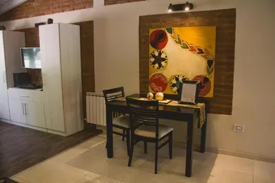 a dining room table with chairs and a painting on the wall at Al Rio Suites in Nono