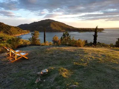 a bench sitting on top of a field next to a lake at Peperina Lago Los Molinos in Villa Ciudad de America