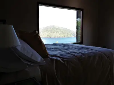 a bed in a room with a large window at Peperina Lago Los Molinos in Villa Ciudad de America