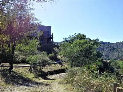 a building on top of a hill with trees at Peperina Lago Los Molinos in Villa Ciudad de America