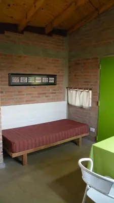 a bed in a room with a brick wall at Cabaña La Miranta in Los Reartes