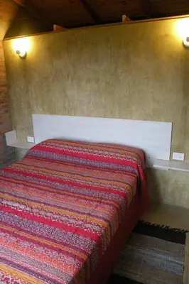 a bed with a red blanket on a wall at Cabaña La Miranta in Los Reartes