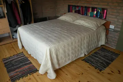 a bed in a bedroom with two rugs at Cabaña La Miranta in Los Reartes
