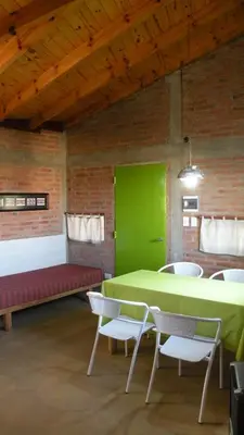 a room with a green table and chairs and a bench at Cabaña La Miranta in Los Reartes