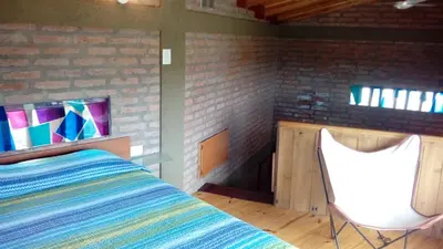 a bedroom with a bed and a chair at Cabaña La Miranta in Los Reartes