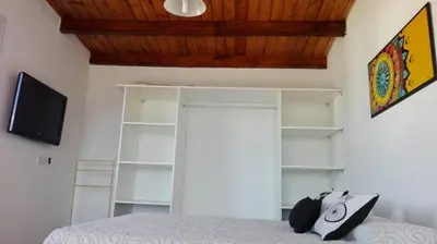 a bedroom with a bed and a tv and shelves at Duplex la Delfina 1 in Villa Carlos Paz
