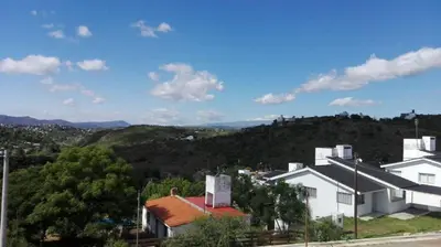 a white house with a hill in the background at Duplex la Delfina 1 in Villa Carlos Paz