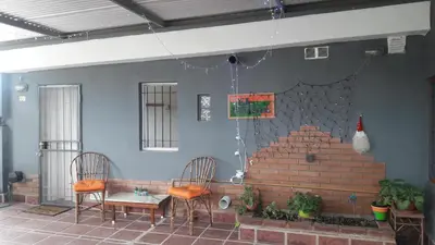 a patio with two chairs and a bench and a wall at Departamento El Nogal in Alta Gracia