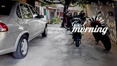 a motorcycle parked next to a car on a street at Departamento El Nogal in Alta Gracia