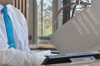 a man with a blue tie sitting at a desk with a laptop at Epic Hotel Villa de Merlo in Merlo
