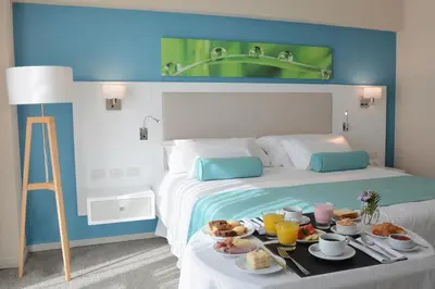 a hotel room with a bed with a tray of food at Epic Hotel Villa de Merlo in Merlo