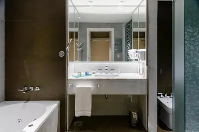 a bathroom with a sink and a tub and a mirror at Epic Hotel Villa de Merlo in Merlo