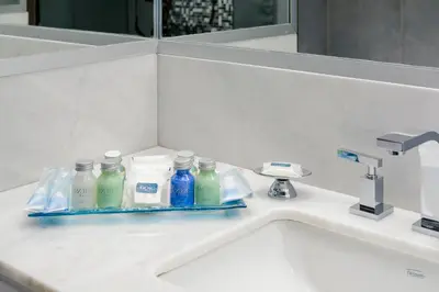 a bathroom sink with bottles of detergent and a mirror at Epic Hotel Villa de Merlo in Merlo