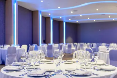 a conference room with white tables and chairs and wine glasses at Epic Hotel Villa de Merlo in Merlo