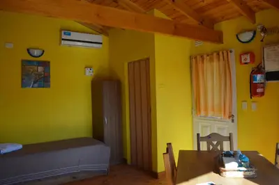 a room with yellow walls and a table and a bed at Cabañas Kumelkalechi in Los Reartes
