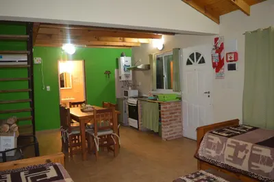 a kitchen with green walls and a table and chairs at Cabañas Kumelkalechi in Los Reartes
