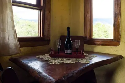 a bottle of wine sitting on a table with two glasses at Cabañas Quisama in Nono