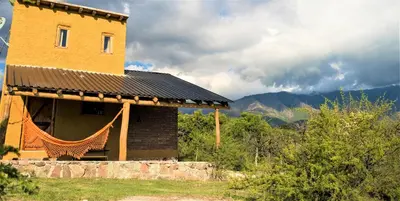a building on a hill with mountains in the background at Cabañas Quisama in Nono