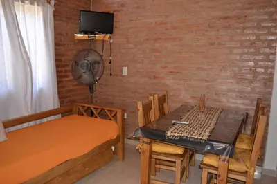 a room with a table and a bed and a dining room at Der Wald cabañas in Los Reartes
