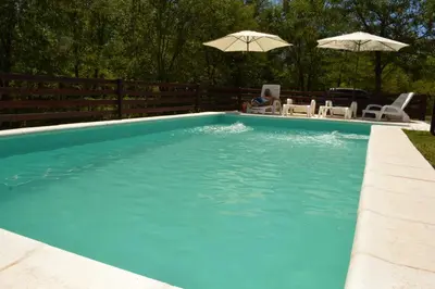 a swimming pool with two chairs and two umbrellas at Der Wald cabañas in Los Reartes