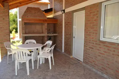 a patio with a table and chairs and a brick wall at Der Wald cabañas in Los Reartes