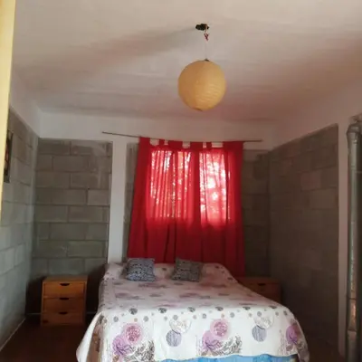a bedroom with a bed with a red curtain at Casas Tierra de Ensueno in Villa Parque Siquiman