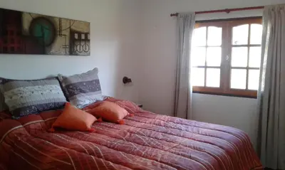 a bedroom with a bed with orange pillows and a window at Isabel in Alta Gracia