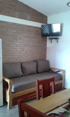 a couch in a living room with a brick wall at Isabel in Alta Gracia