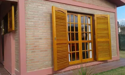a house with wooden shutters on the side of it at Isabel in Alta Gracia